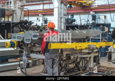 Arbeiter bei der Montage von Komponenten für die Herstellung von Mähdreschern oder Traktoren in der industriellen Fertigungsstraße. Stockfoto