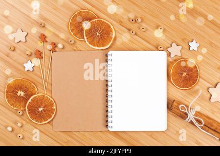 Weihnachtsbäckerei Hintergrund mit offenem leerem Notizbuch, getrockneten Orangenscheiben, Zimtstangen und Holzdekorationen. Flach liegend. Speicherplatz kopieren. Stockfoto