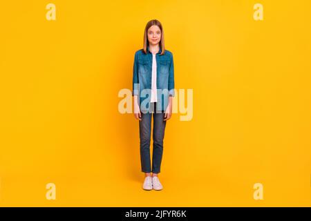 Foto in voller Größe von fröhlich zufrieden Mädchen stehen haben gute Laune auf hellgelben Hintergrund isoliert Stockfoto