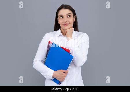 Studentin hält Bücher isoliert auf grauem Hintergrund im Studio. Englische Sprachschule, Bildungskonzept. Denkender Student. Stockfoto