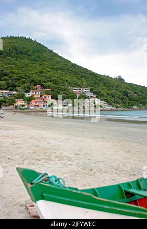 ARMACAO, FLORIANOPOLIS, SANTA CATARINA, BRASILIEN. Blick auf das Meer, am frühen Morgen vom Strand. Im Vordergrund ein buntes Boot am Strand. Stockfoto