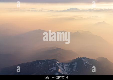 Nebelschwaden bei Sonnenuntergang über den majestätischen Lepontine Alpen und dem Monte Rosa in den Wolken, Blick aus dem Flugzeug, Schweiz, Europa Stockfoto