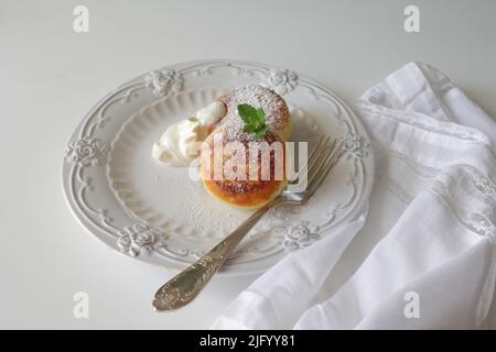 Käsekuchen Frühstück oder Dessert Syrniki, Quark Quark Pfannkuchen. Quark-Pfannkuchen, Syrniki, Ricotta-Fritten auf weißer Keramikplatte. Hea Stockfoto