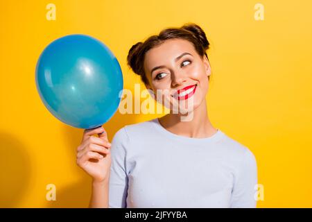 Foto von verträumt süße Dame tragen lange Ärmel halten suchen blauen Ballon isoliert gelben Hintergrund Stockfoto