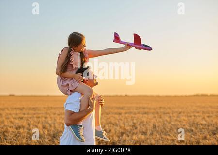 Nettes Mädchen, das auf der Schulter des Vaters reitet Stockfoto