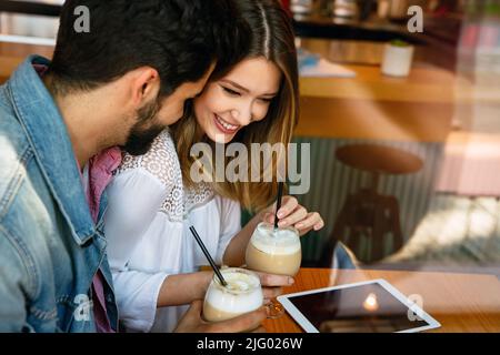 Schönes junges Paar, das im Café sitzt und Spaß mit dem Tablet hat. Studenten während der Pause im Café. Stockfoto