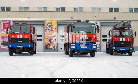 Minsk, Weißrussland - 21. Januar 2022: Drei Feuerwehrfahrzeuge in der Nähe des Gebäudes der Feuerwehrhelfer. Vorderansicht Stockfoto