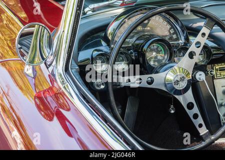 Andover, MA, USA, 26. Juni 2022: Nahaufnahme des Lenkrads in einem hellen Chevrolet Corvette Oldtimer der Ära red1950s - 1960s. Stockfoto