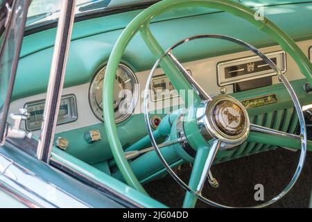 Andover, MA, USA, 26. Juni 2022: Nahaufnahme des Lenkrads in einem pastellgrünen Dodge-Oldtimer der Ära 1950s - 1960s. Stockfoto