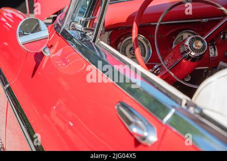 Nahaufnahme des Lenkrads in einem hellen Oldtimer der Ära red1950s - 1960s. Stockfoto