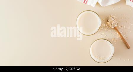 Hafermilch im Glas, Flocken von gebackenem Getreide. Milchersatz, Milch für Vegetarier. Flatlay. Speicherplatz kopieren. Stockfoto