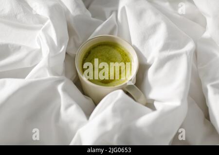 tasse Matcha-Tee im Bett zu Hause Stockfoto
