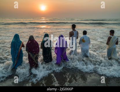 Mumbai, 22. Januar 2014: Devotees beten zu Sun Lord am Juhu Beach auf Chhath Puja Festival mit Sonnenuntergang im Hintergrund, Mumbai, Maharashtra, Indien Stockfoto