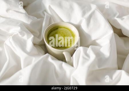 tasse Matcha-Tee im Bett zu Hause Stockfoto