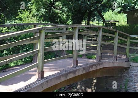 Eine kleine gebogene Holzbrücke über den Fluss Horner bei Bossington in Somerset Stockfoto