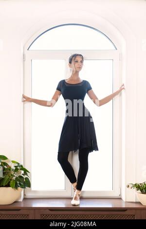 Erwachsene Balletttänzerin in einem schwarzen Tutu üben vor der Aufführung in schwarzem Tutu Stockfoto