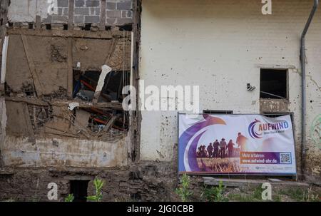 Altenahr, Deutschland. 06.. Juli 2022. Ein Plakat mit der Aufschrift 'Aufwind Ahr' lehnt sich an die Fassade eines zerstörten Hauses in Altenahr. Am 14. Juli jährt sich die Katastrophe zum ersten Mal. Quelle: Boris Roessler/dpa/Alamy Live News Stockfoto