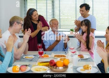 Glückliche Mutiethnizität und Mehrgenerationenfamilie feiern Großväter Geburtstag im Wohnzimmer zu Hause. Stockfoto