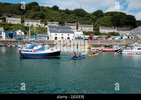 Touristen, die im Innenhafen von Porthleven, Cornwall, Kajakfahren Stockfoto