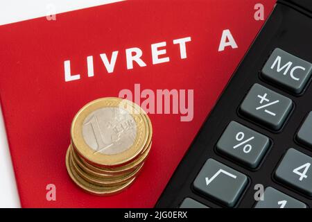 Frankreich: Ein Büchlein mit einem Stapel Euro-Münzen und einem Taschenrechner. Das Livret A ist ein reguliertes französisches Sparkonto Stockfoto