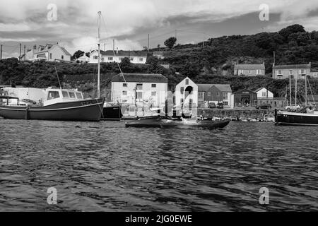 Touristen, die im Innenhafen von Porthleven, Cornwall, Kajakfahren Stockfoto