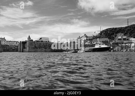 Touristen, die im Innenhafen von Porthleven, Cornwall, Kajakfahren Stockfoto