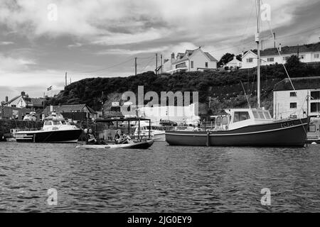 Touristen, die im Innenhafen von Porthleven, Cornwall, Kajakfahren Stockfoto