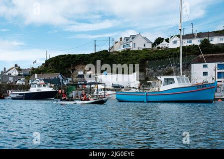 Touristen, die im Innenhafen von Porthleven, Cornwall, Kajakfahren Stockfoto