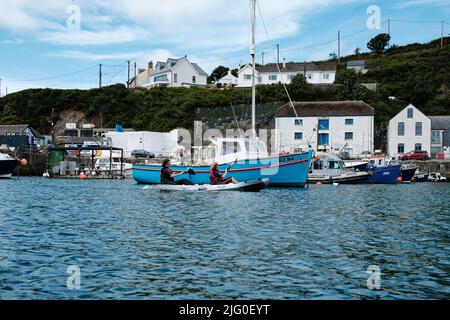 Touristen, die im Innenhafen von Porthleven, Cornwall, Kajakfahren Stockfoto