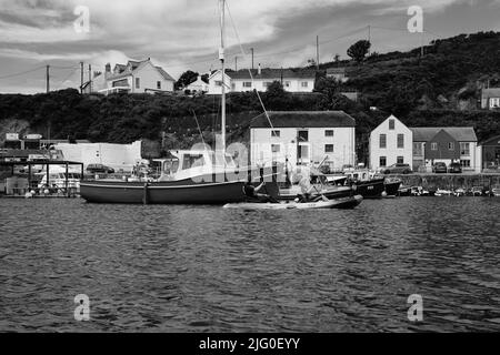 Touristen, die im Innenhafen von Porthleven, Cornwall, Kajakfahren Stockfoto