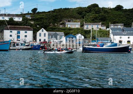 Touristen, die im Innenhafen von Porthleven, Cornwall, Kajakfahren Stockfoto