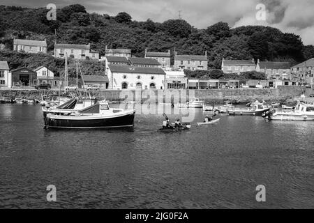 Touristen, die im Innenhafen von Porthleven, Cornwall, Kajakfahren Stockfoto