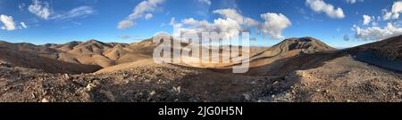 Einsames Panorama der Vulkanlandschaft mit blauem Himmel. Eine Straße führt durch die erdigen Hügel, groß als Hintergrund, Kopfzeile oder Banner mit Kopierraum Stockfoto