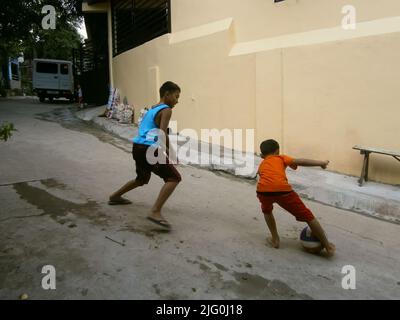 Zwei junge Jungs spielen Football auf der Dorfstraße Stockfoto