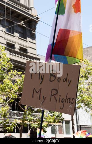 Protestschild und Plakat mit der Aufschrift 'Mein Körper Meine Rechte', das mit einer Stolzflagge zusammengehalten wird. Foto aufgenommen in San Francisco, Kalifornien Stockfoto