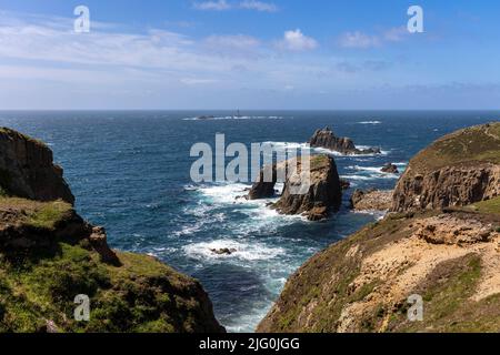 Blick auf den Küstenwanderweg zwischen Gwennap Head und Lands End. Enys Dodnan Bogen mit Longships Leuchtturm in der Ferne Stockfoto