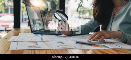 Steuerprüfer und Finanzprüfer, die durch die Lupe schauen und Finanzpapiere, Dokumente und Berichte des Unternehmens überprüfen Stockfoto