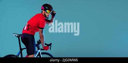 Flyer mit Radprofi auf dem Fahrrad in roter Sportuniform, Schutzbrille und Helm auf blauem Hintergrund. Konzept des aktiven Lebens, der Ruhe, des Reisens Stockfoto