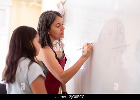 Lehrer erklärt einem Grundschüler eine mathematische Übung. Konzept des Lernens, der Bildung und der Entwicklung von Kindern. Stockfoto