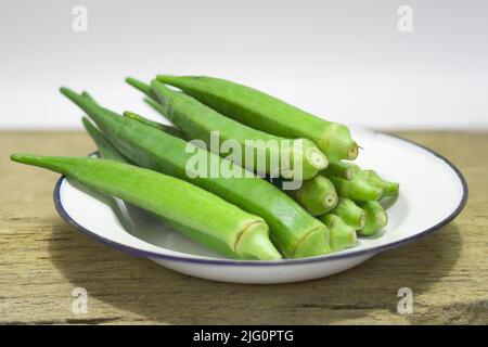 Nahaufnahme frischer Okra-Früchte (abelmoschus esculentus) auf Holzhintergrund Stockfoto