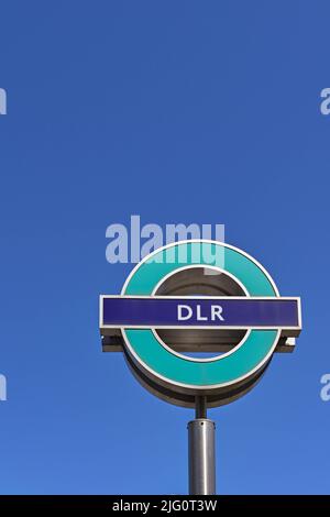 London, England - 2022. Juni: Schild vor dem Eingang zu einem Bahnhof auf der Docklands Light Railway, isoliert vor einem tiefblauen Himmel Stockfoto