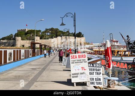 Kusadasi, Türkei - Juni 2022: Besucher, die vom byzantinischen Schloss auf der Taubeninsel im Hafen von Kusadasi aus spazieren gehen Stockfoto
