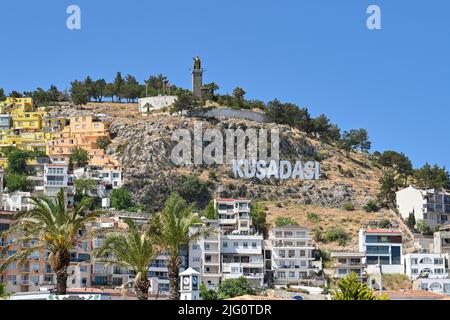 Kusadasi, Türkei - Juni Mai 2022: Großes Schild auf dem Hügel mit Blick auf den Hafen von Kusadasi Stockfoto