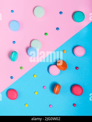 Farbenfrohe Flatlays aus Makronen und Bonbons auf rosa und blauem Hintergrund Stockfoto