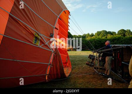 Ein Heißluftballon. Der Aeronaut (Pilot) feuert die Gasbrenner an, um den Ballon steigen zu lassen. Stockfoto