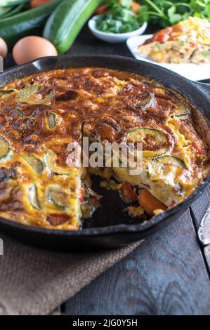 Gesundes Eiergericht mit im Ofen gebackenen Frittata mit Gemüse in einer gusseisernen Pfanne Stockfoto