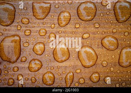 Horizontaler Hintergrund aus lackiertem verbranntem Holz mit glänzenden Wassertropfen aus dem Regen, nassen Holzplanken Stockfoto