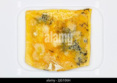 Käse mit Schimmel. Ein großes Stück Käse mit Löchern, das lange Zeit verdorben und mit Schimmel bedeckt war. Wunderschöne Aussicht auf verdorbenes Essen. Gelber Schimmel Stockfoto