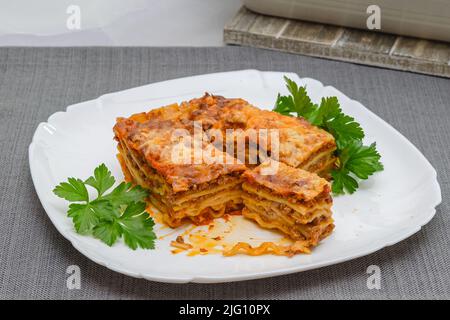 Rinderlasagne mit frischer Petersilie aus nächster Nähe auf Weiß serviert Platte Stockfoto