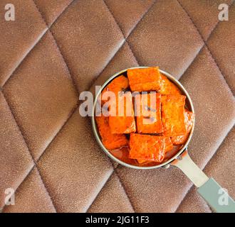 Paneer Rogan josh, indische Kashmiri-Küche aus Hüttenkäse, Kräutern, Gewürzen, hat dicke Soße. Serviert in einer gusseisernen Schüssel auf rustikalem Holzhintergrund. Stockfoto